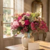 Lussuoso bouquet Sinfonia Rosa con peonie, rose e garofani accesi, illuminato dalla luce del sole su tavolo in legno.