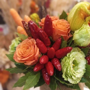 Dettaglio fiori e ortaggi con peperoncini rossi brillanti, rose arancioni e lisianthus verdi